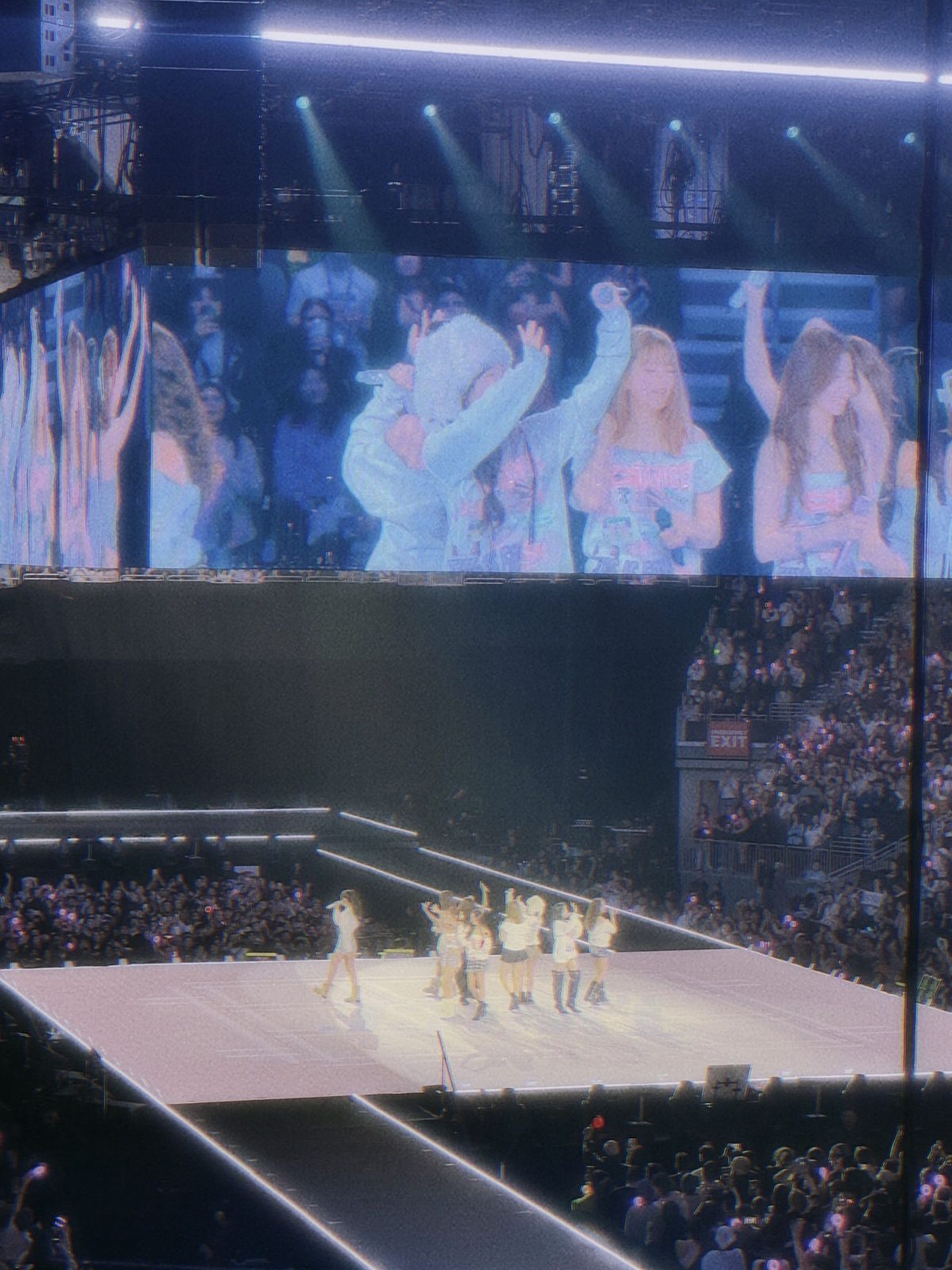 TWICE performing at the THIS IS FOR World Tour, the group on a long stage mirrored on the giant screen above