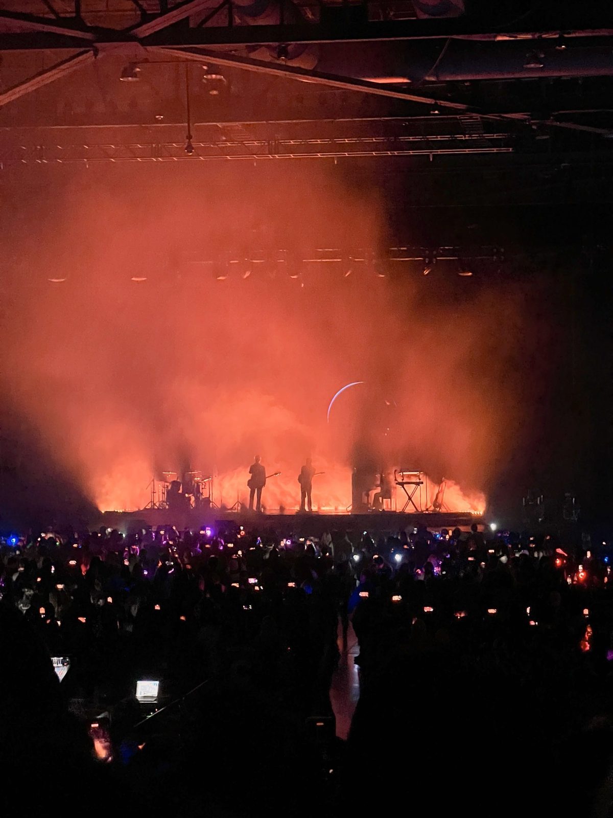 The Rose performing at the Dawn to Dusk World Tour, Oct 2023, the band silhouetted against red haze and a crescent moon